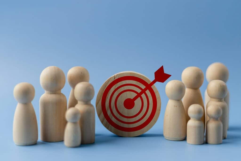 Business target concept. Wooden figures of people and a target on a blue background.